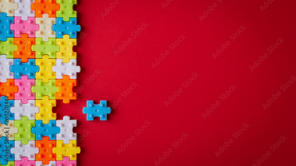 Colors plastic jigsaw puzzle on red paper background, Missing one jigsaw puzzle to complete with copy space. - obrazy, fototapety, plakaty 