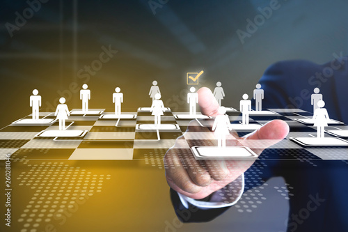 Business administrator selecting a man in action of manpower or human resource planning or business organisation on a virtual checkerboard or draughtboard.