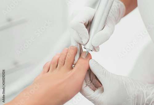 Podolog removes the cuticle on the nails using hardware. photo