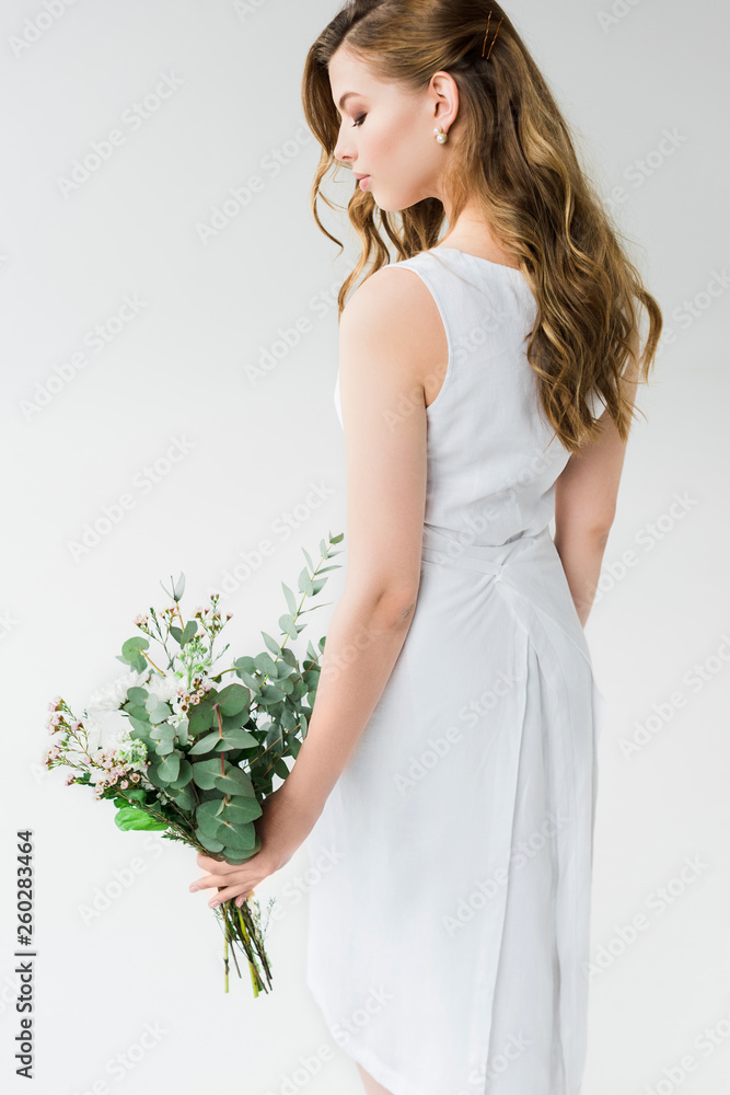 attractive woman in elegant dress looking at flowers on white attractive woman in elegant dress looking at flowers on white