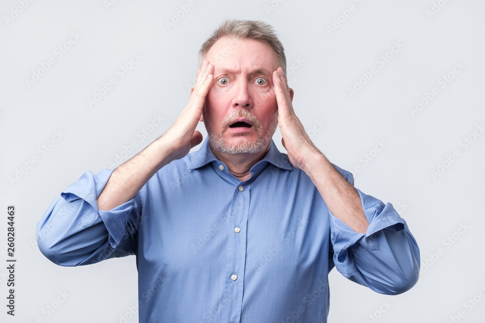 senior man in suit holding head with both hands senior man in suit holding head with both hands