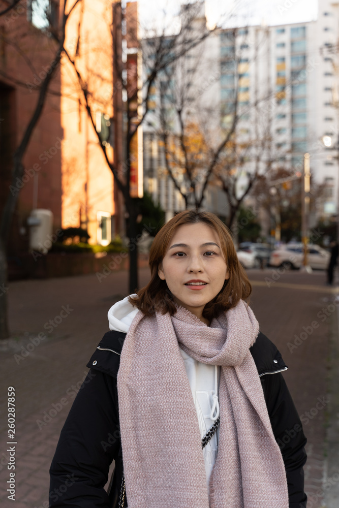 Chinese girl standing in a korean street in Jeju island wearing a black jacket and pink scarf ,looking happy Chinese girl standing in a korean street in Jeju island wearing a black jacket and pink scarf ,looking happy