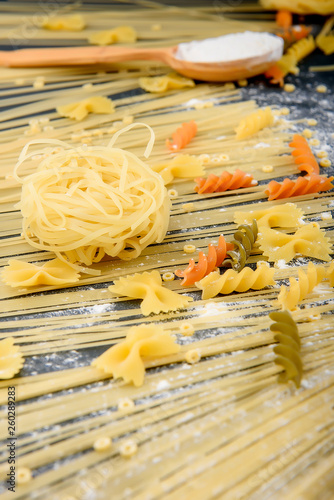 preparing pasta, eggs, flour, various types of pasta, spaghetti, on dark background.from above.