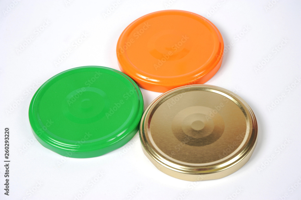 Screw caps for glass jars. For canning, canned food. Orange, green, golden caps on white background Screw caps for glass jars. For canning, canned food. Orange, green, golden caps on white background