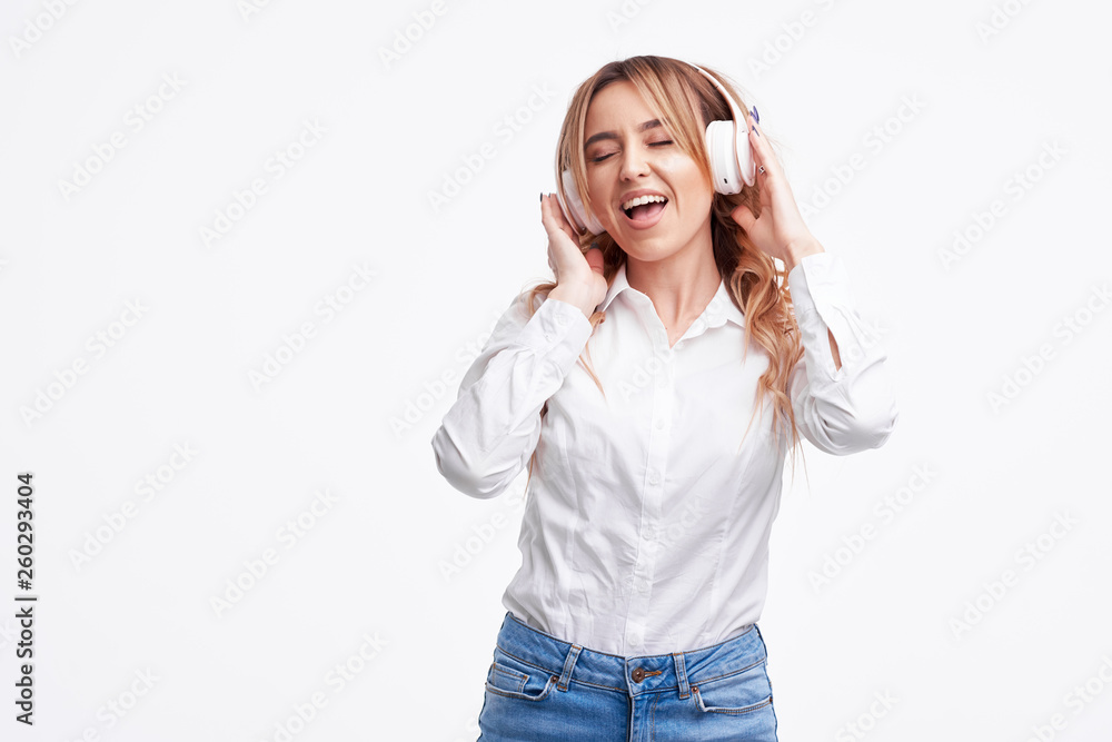 Wireless connection. Portrait of young beautiful woman posing isolated over white background listening music with headphones. Wireless connection. Portrait of young beautiful woman posing isolated over white background listening music with headphones.