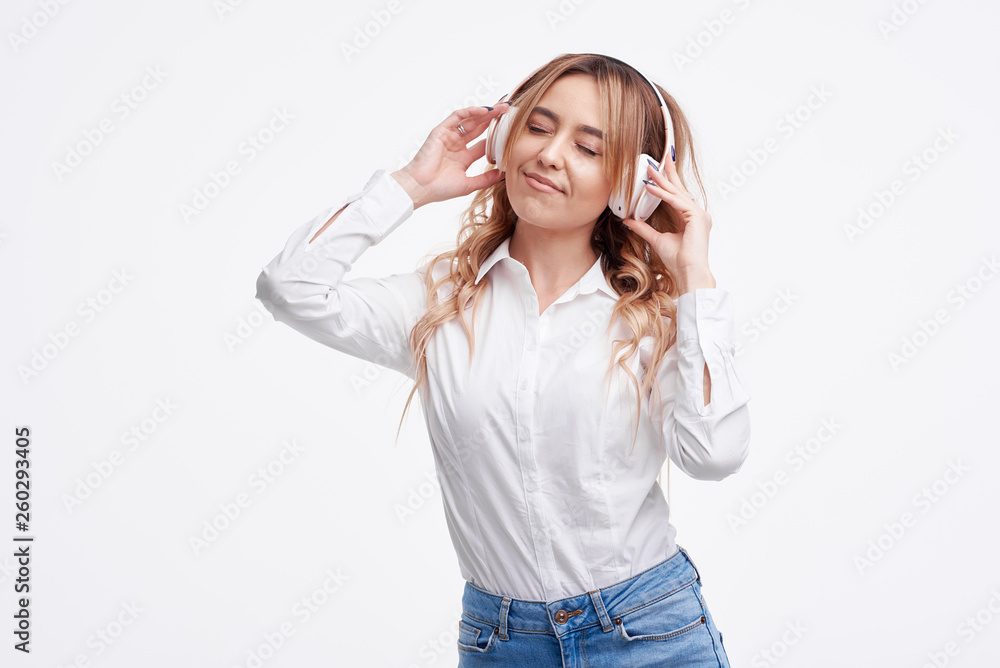 Wireless connection. Portrait of young beautiful woman posing isolated over white background listening music with headphones. Wireless connection. Portrait of young beautiful woman posing isolated over white background listening music with headphones.
