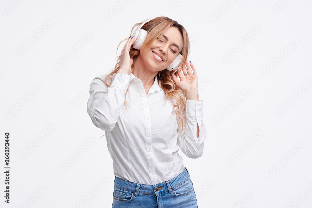 Wireless connection. Portrait of young beautiful woman posing isolated over white background listening music with headphones. Wireless connection. Portrait of young beautiful woman posing isolated over white background listening music with headphones.