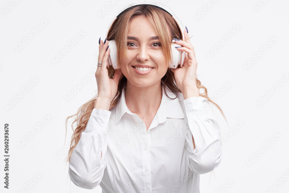 Wireless connection. Portrait of young beautiful pleasure woman posing isolated over white background listening music with headphones. Wireless connection. Portrait of young beautiful pleasure woman posing isolated over white background listening music with headphones.