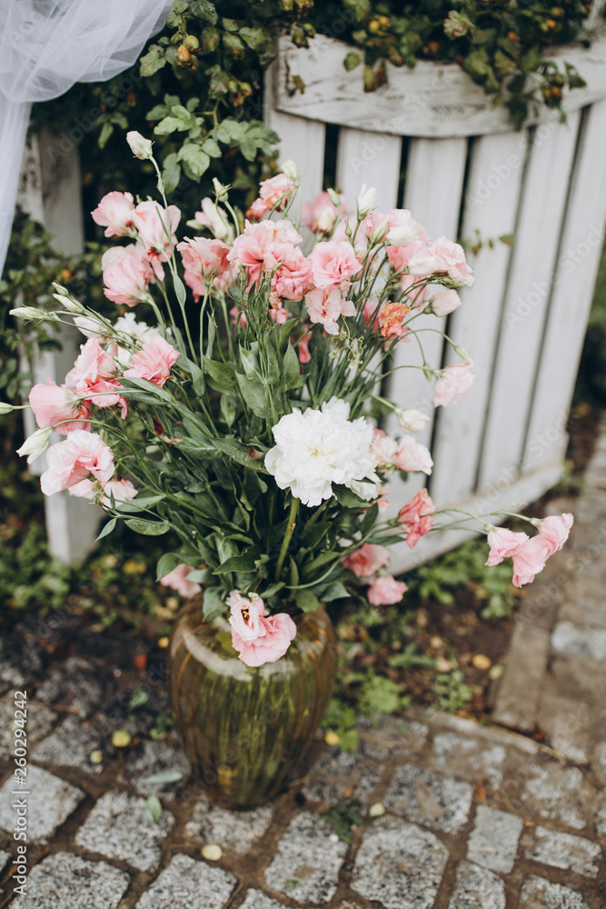 arrangement of white and pink flowers in a vase on a stone walkway arrangement of white and pink flowers in a vase on a stone walkway