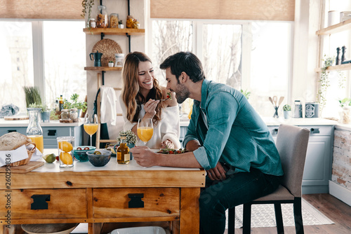 Try it! Beautiful young couple enjoying healthy breakfast while sitting in the kitchen at home