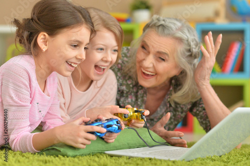 Grandmother and granddaughters playing on laptop