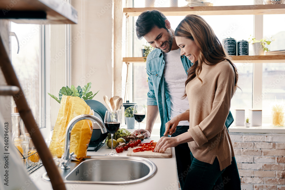Loving couple. Beautiful young couple cooking dinner while standing in the kitchen at home