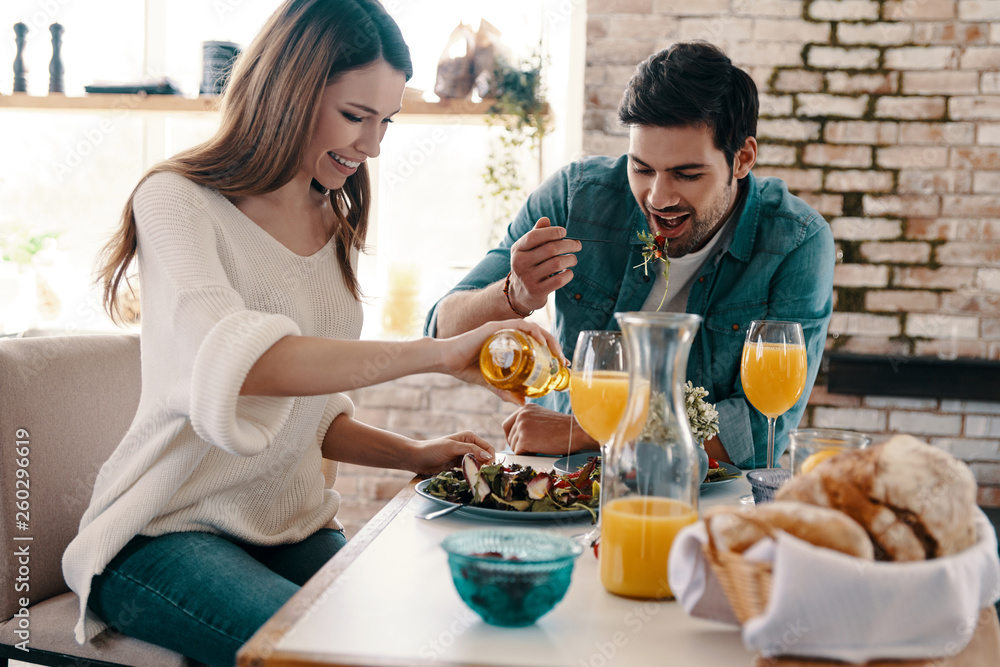 Good meal in a good company. Beautiful young couple enjoying healthy breakfast while sitting in the kitchen at home Good meal in a good company. Beautiful young couple enjoying healthy breakfast while sitting in the kitchen at home
