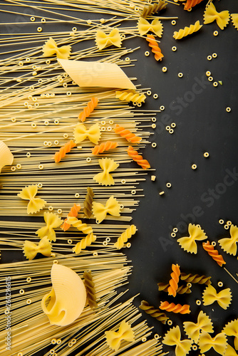 Variety of types and shapes of Italian pasta on dark background from above. Italian cuisine food concept and menu design. Dry pasta background. Top view. Flat lay. Copy space