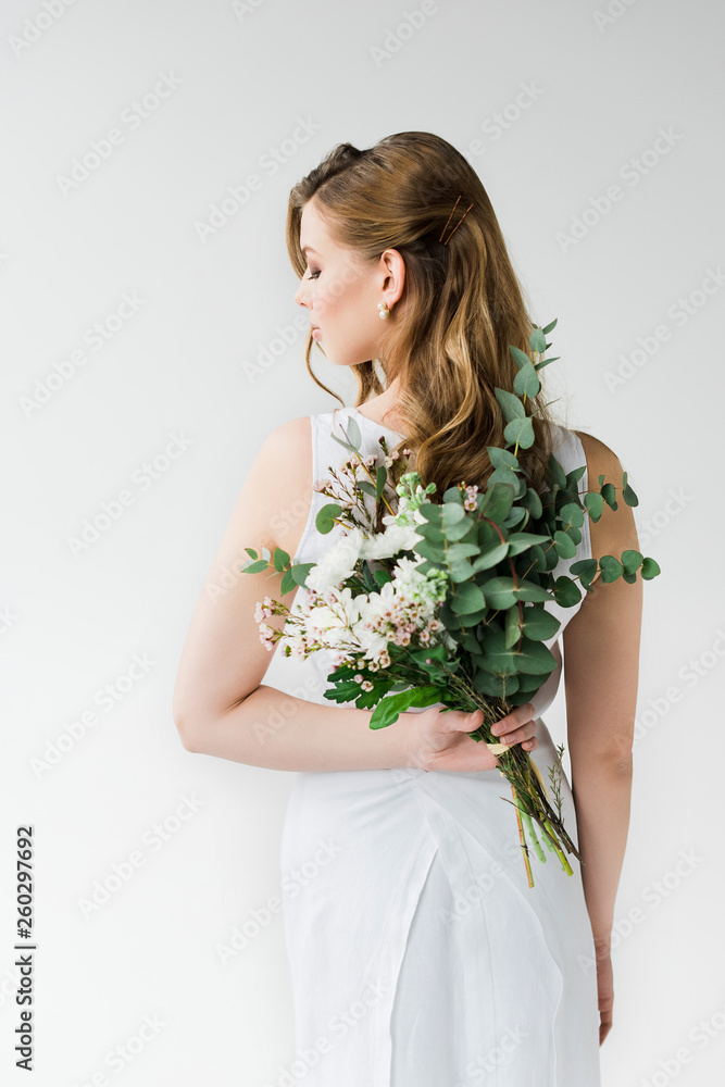 back view of woman in elegant dress holding flowers behind back on white back view of woman in elegant dress holding flowers behind back on white