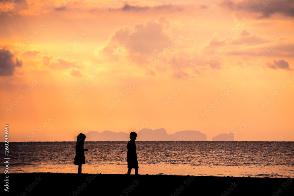 Children playing on the beach at the sunset. Silhouette child and tropical sky in summer season