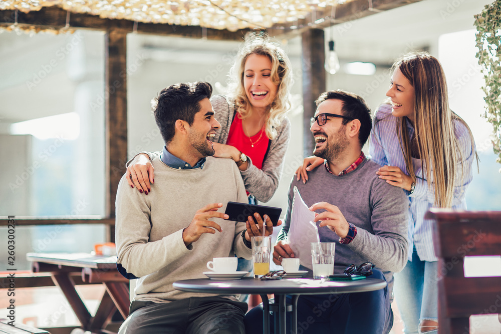 Group of four friends having fun a coffee together. Two women and two men at cafe talking laughing and using digital tablet. Group of four friends having fun a coffee together. Two women and two men at cafe talking laughing and using digital tablet.
