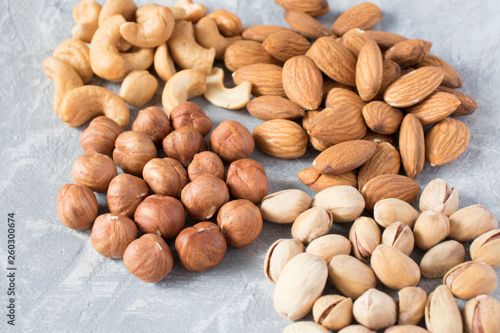 Obraz premium mixed nuts on a gray background. Walnut, pistachios, almonds, hazelnuts and cashews, walnut.