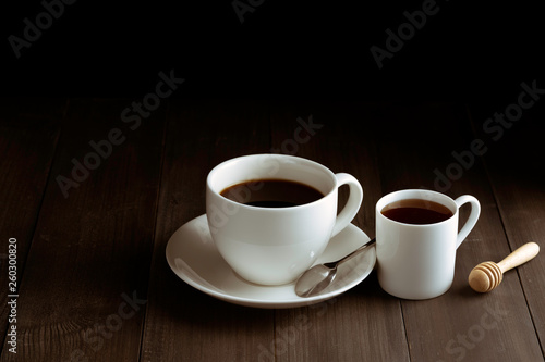 Coffee cup and sweet honey on black wooden background.