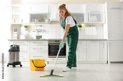 Professional janitor cleaning floor with mop in kitchen