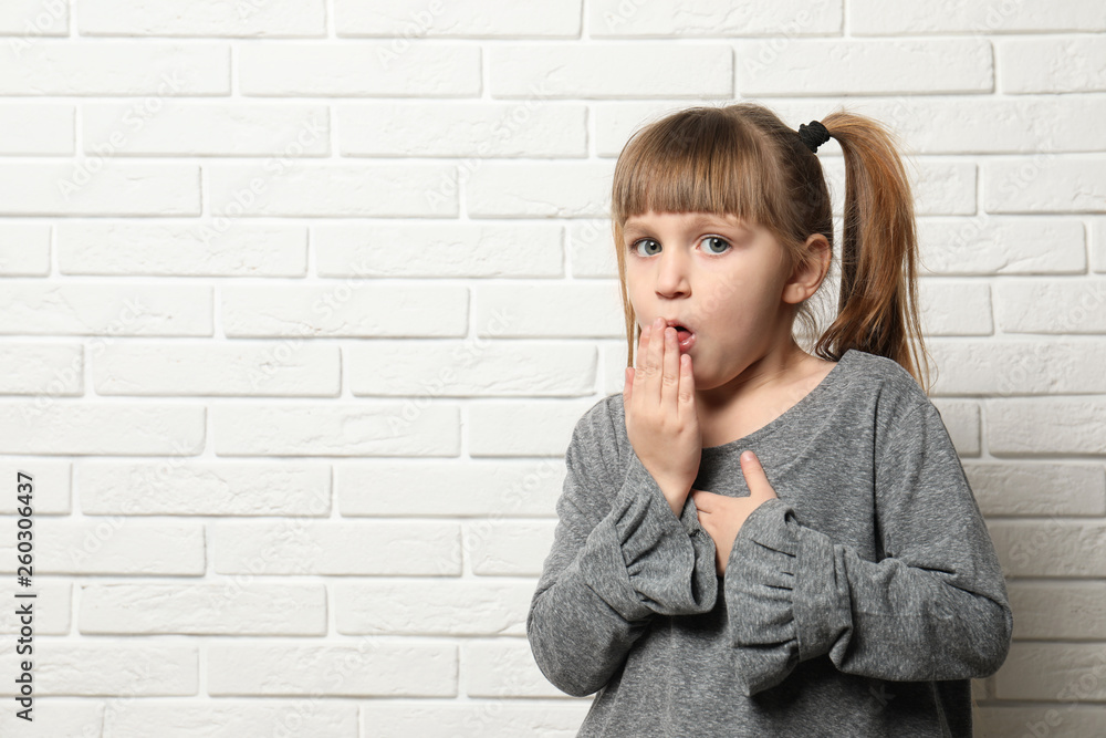 Cute little girl coughing near brick wall. Space for text Cute little girl coughing near brick wall. Space for text