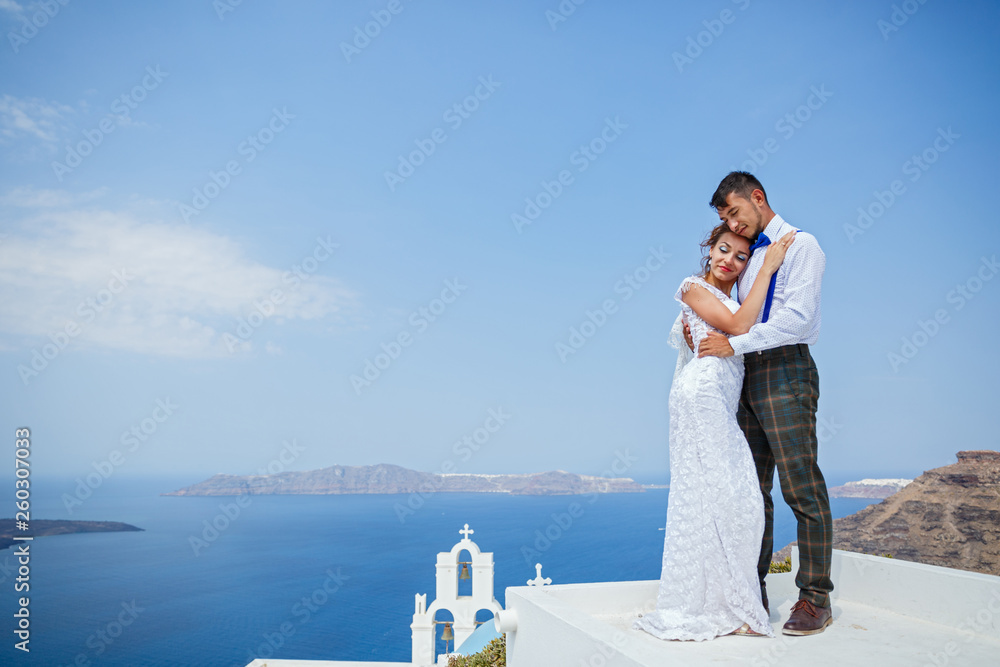 Bride and groom stand next to the sea