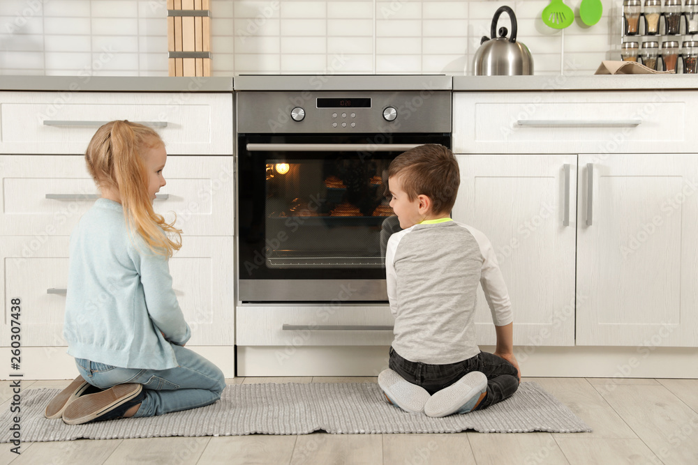 Little kids waiting for preparation of buns in oven at home Little kids waiting for preparation of buns in oven at home