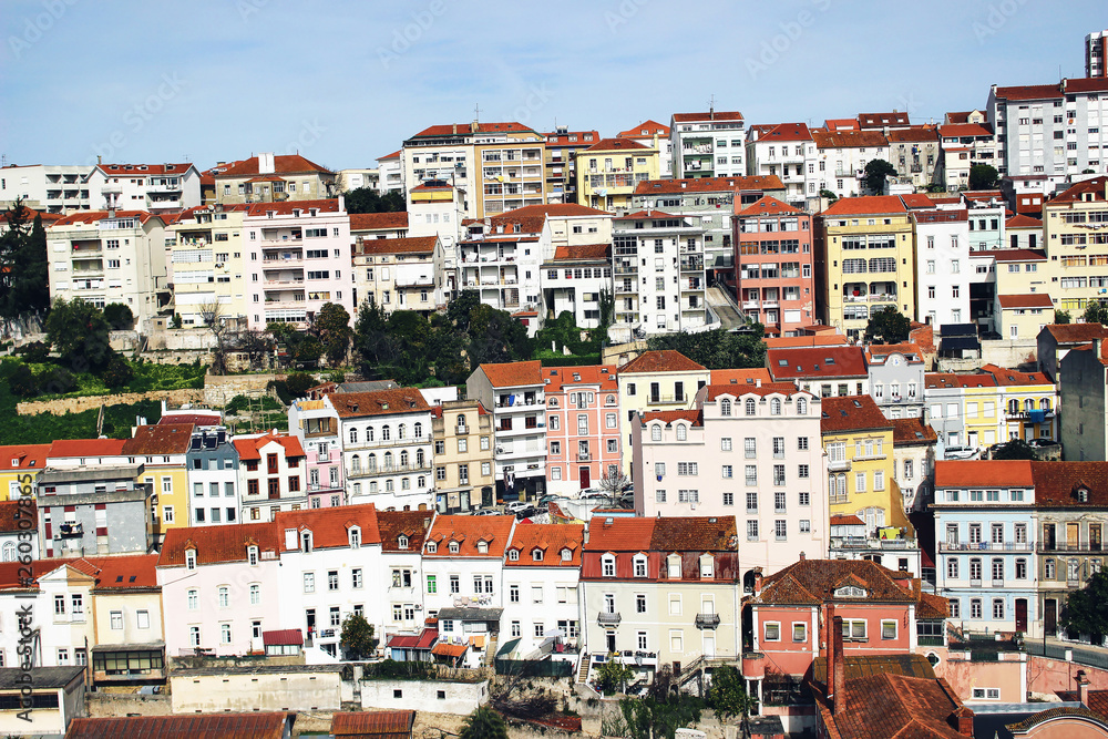 Panorama of Coimbra town, former medieval capital of Portugal. View of colorful houses and roof tops over blue sky. European travel concept.