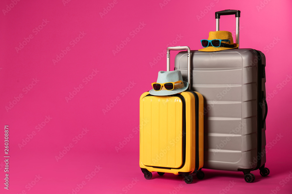 Stylish suitcases with hats and sunglasses on color background. Space for text Stylish suitcases with hats and sunglasses on color background. Space for text