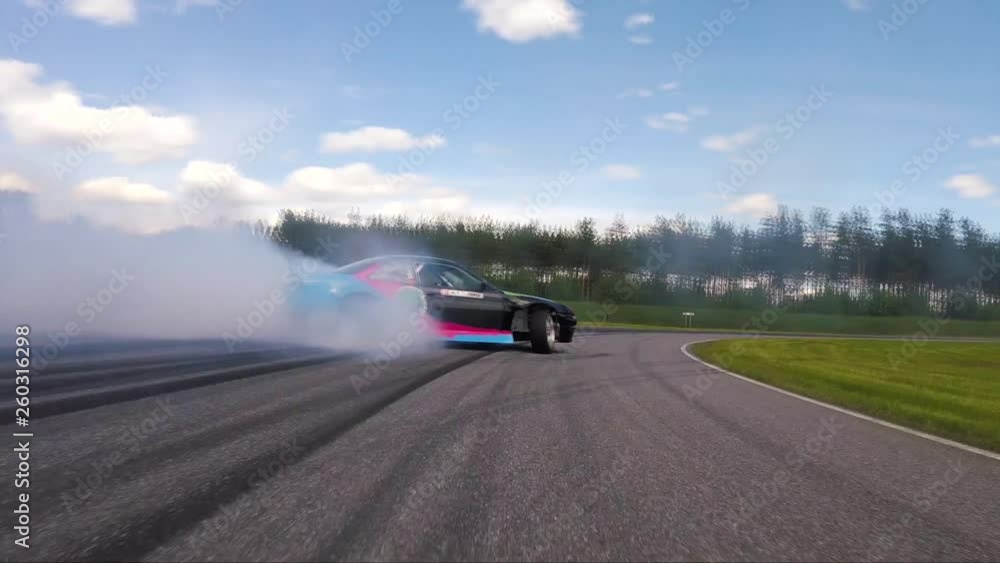 Drifting Back Back view of a car drifting on a circuit with smoke and dangerous ...