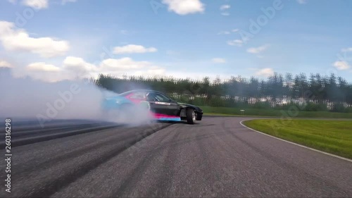 Back view of a car drifting on a circuit with smoke and dangerous curves. photo