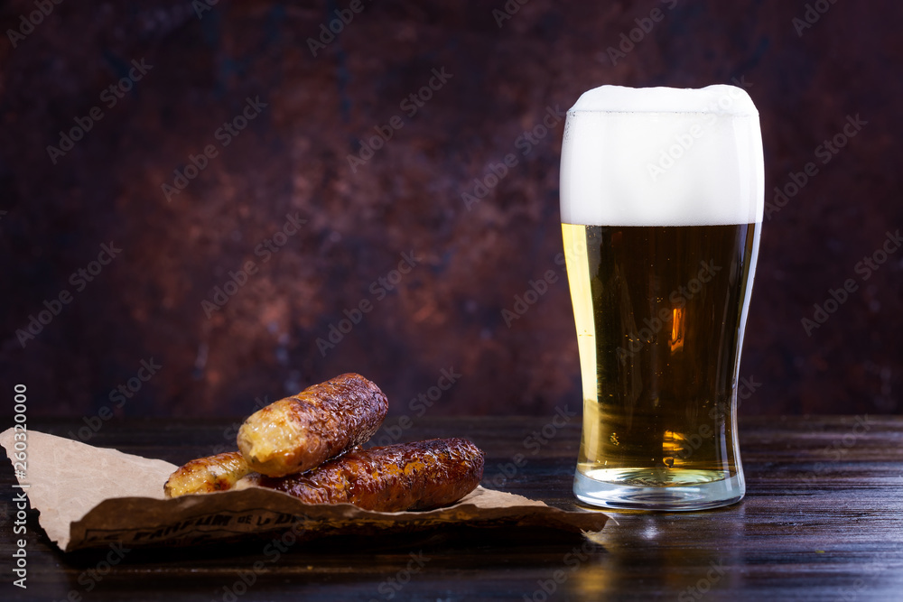 glass of beer with foam, fried sausages on a dark background glass of beer with foam, fried sausages on a dark background