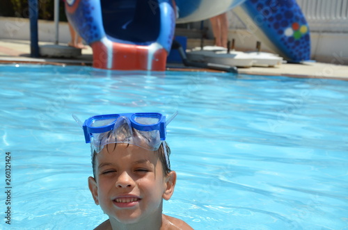 Teenager boy wearing mask swimming in the pool. Happy holiday concept. Cute happy little boy swimming and snorking in the sea ocean in crystal blue water photo