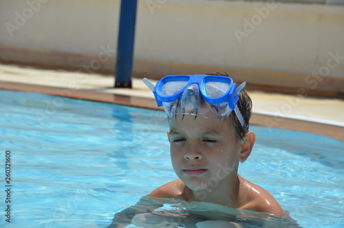 Teenager boy wearing mask swimming in the pool. Happy holiday concept. Cute happy little boy swimming and snorking in the sea ocean in crystal blue water © Dilya