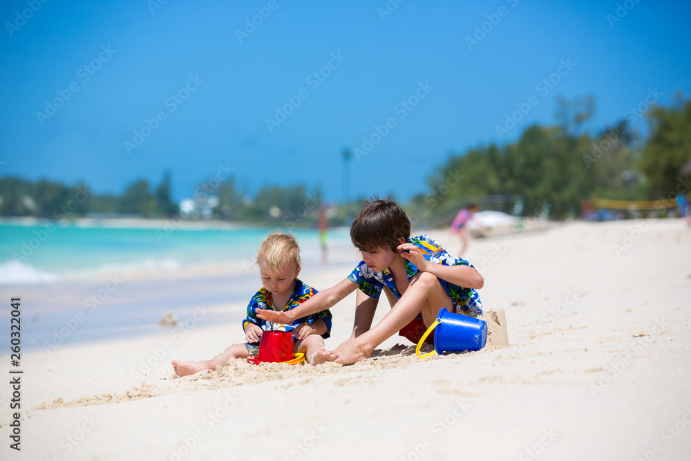 Happy beautiful fashion family, mom and children, dressed in hawaiian shirts, playing together on the beach