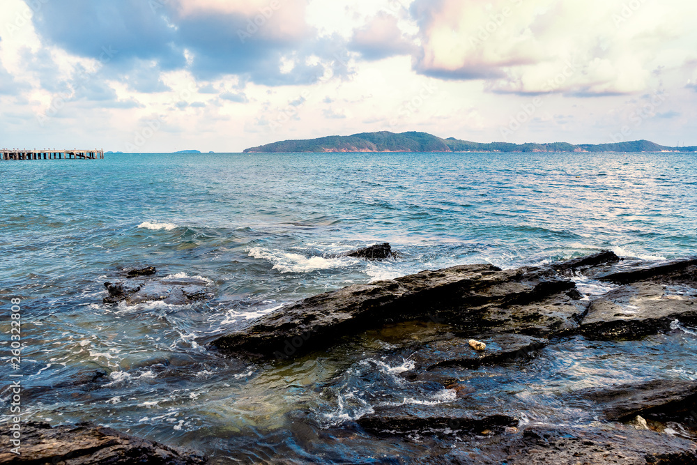 Sea wave and rock with island and jetty background. Thailand.