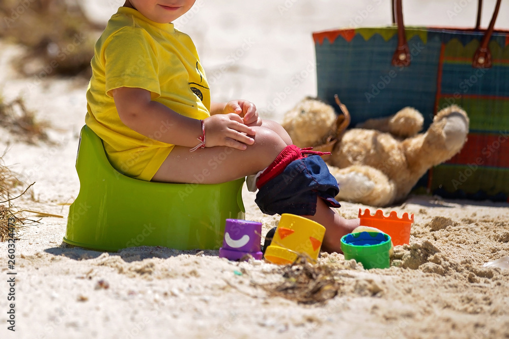 Little toddler boy, learning potty training on the beach on a tropical island