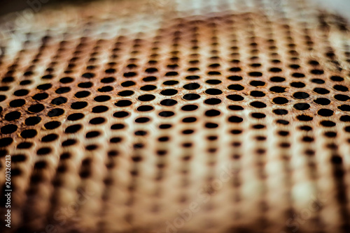 Perforated brown rusty iron sheet texture. Surface with depth of field, industrial mesh. Horizontal background