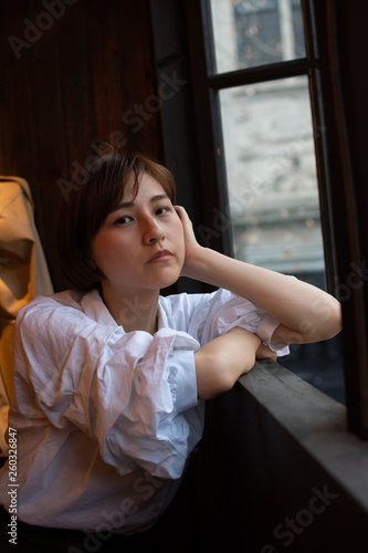 Asian chinese girl having a good time at a coffee shop in hangzhou, China. wearing a white shirt, smiling