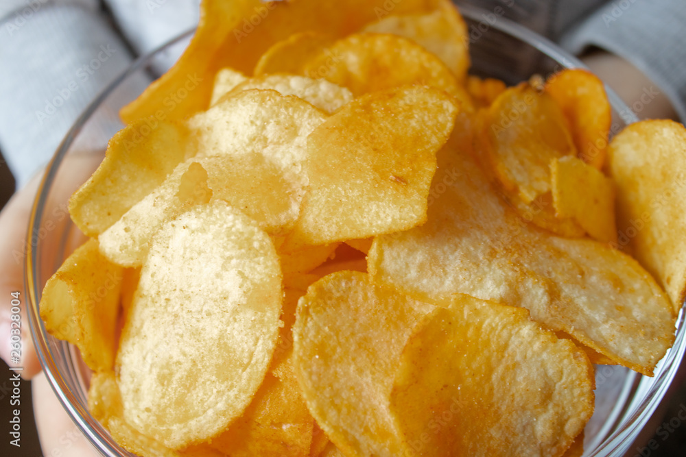 Chips close-up, in a glass container. A child holds a bunch of yellow chips. Chips close-up, in a glass container. A child holds a bunch of yellow chips.