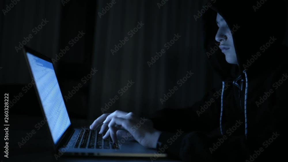Computer Robber Hacker's hacking into the computer network. A young guy in a dark room ...