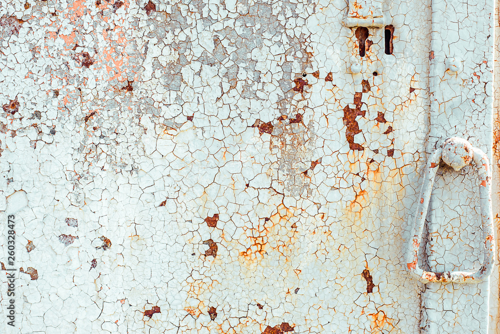 Texture of rusty metal door with handle, painted white which became orange from rust in some places. Horizontal texture of cracked white paint