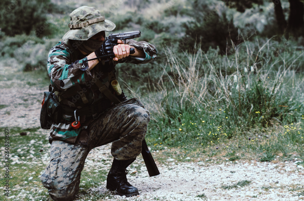 Special forces soldier holding hand gun and knife in crouching shooting position StockFoto