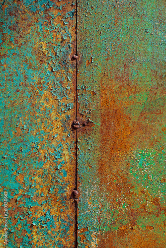 Texture of rusty metal, painted green which becames orange from rust. Vertical texture of cracked paint on rusty welded steel sheets photo