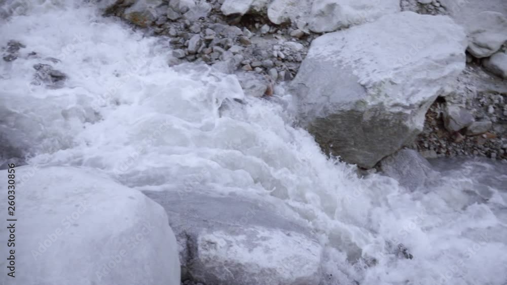 A stormy river of mountain water flows down through large stones A stormy river of mountain water flows down through large stones
