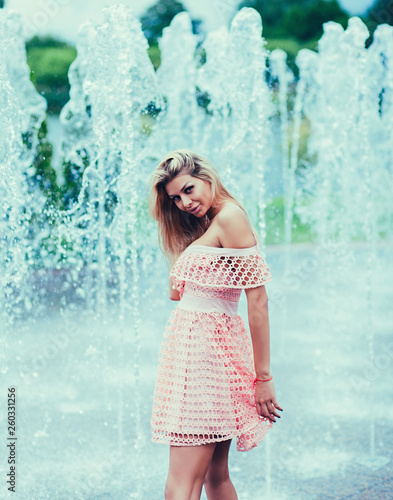 Portrait of a cute and gorgeous woman in fashion dress posing on fountain background