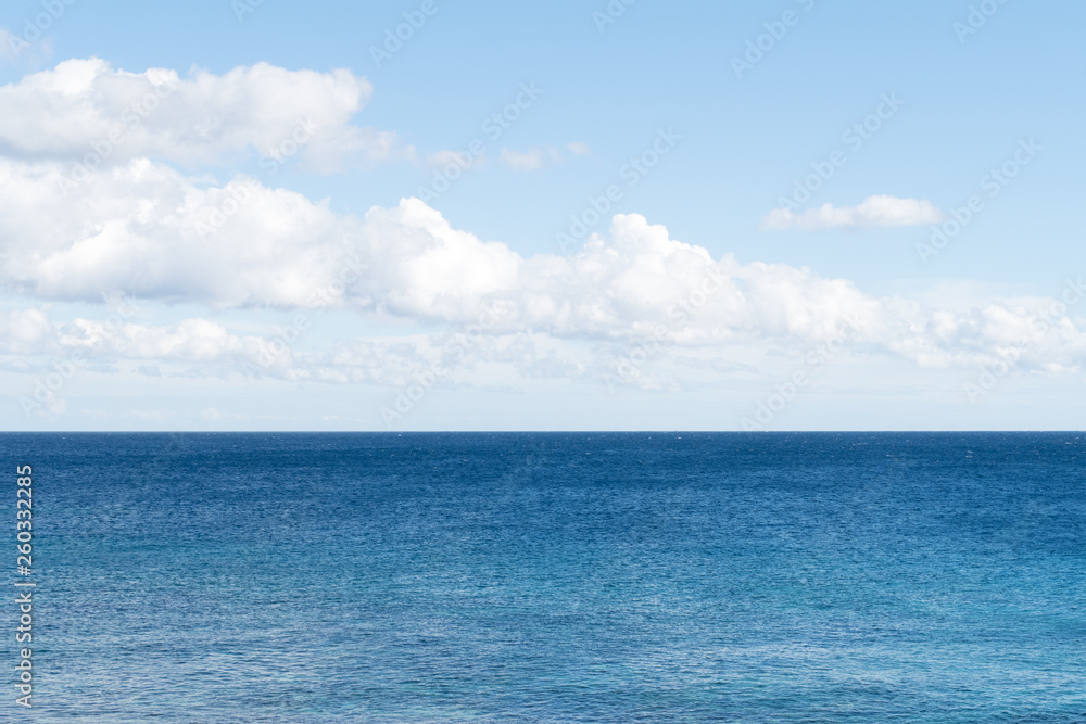 Clean, clear beautiful deep blue Atlantic Ocean backdrop wallpaper against a blue sky with few clouds and lots of copy space. 
