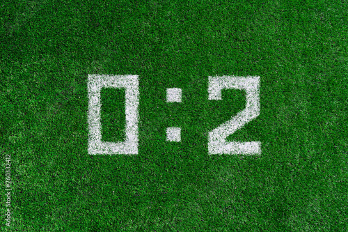White numbers zero and two are drawn on green grass  football score
