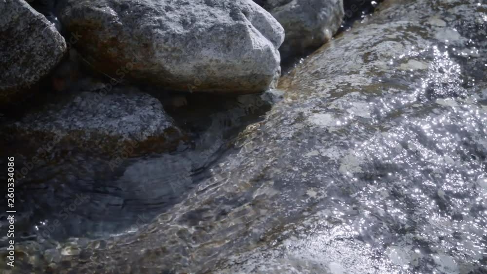 Clean, mountain drinking water flows down from a large stone Clean, mountain drinking water flows down from a large stone