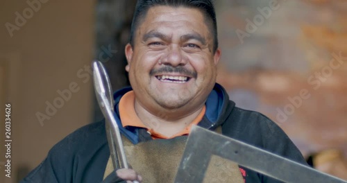 Mexican or Hispanic man holding tools smiling and looking at the camera